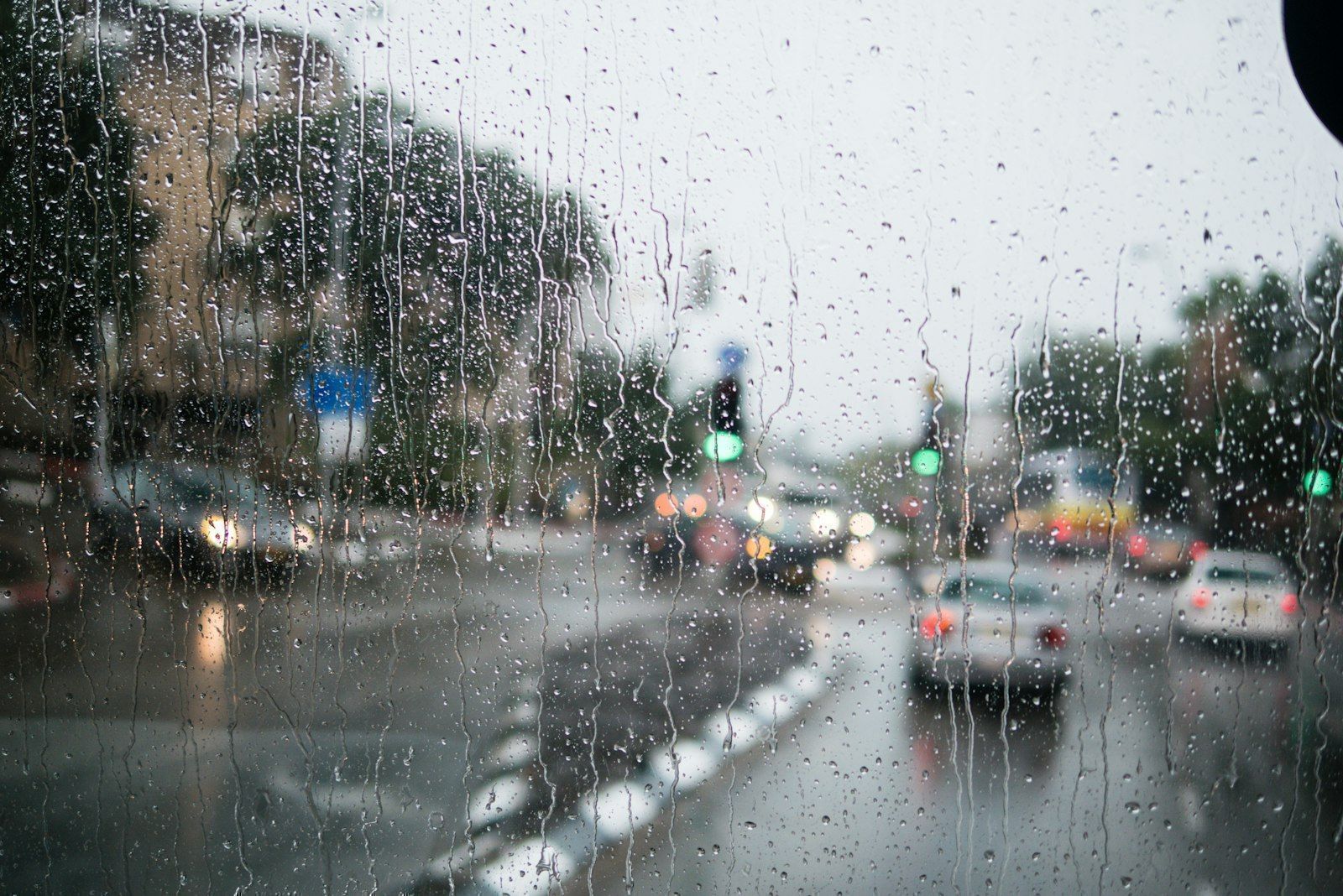 Calle bajo la lluvia vista a través de un parabrisas mojado