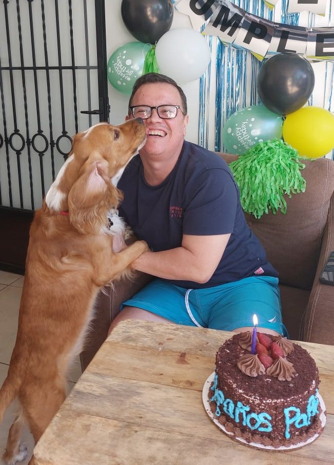 Ricardo Peña sonríe junto a su perro durante una celebración familiar