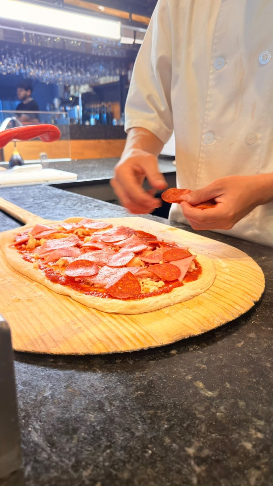 Pizza armada en la pala antes de entrar al horno de leña en Santo Olivo