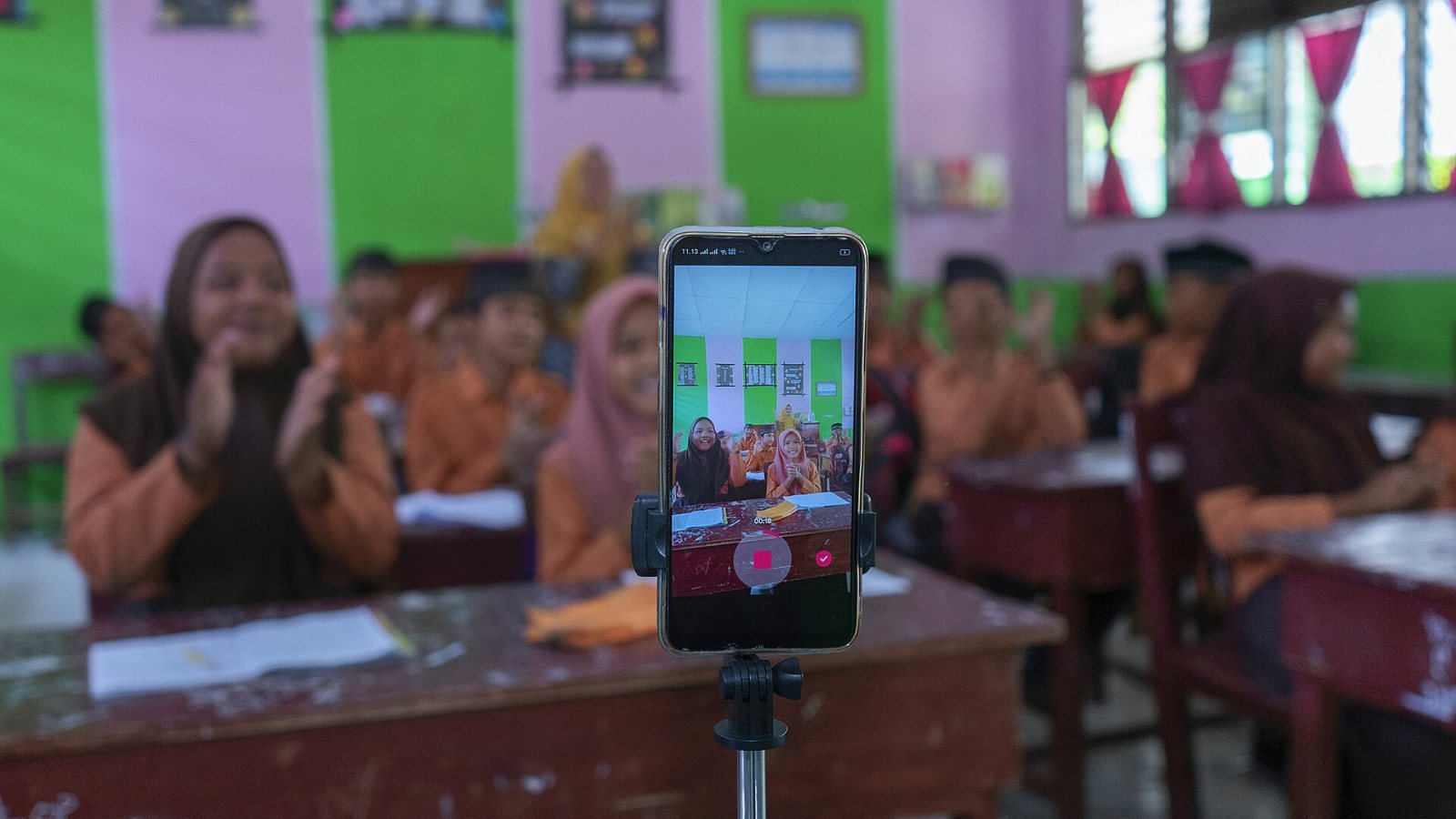 Teléfono celular frente a un grupo de alumnos en un salón de clases